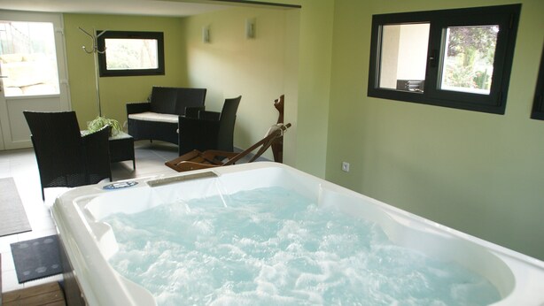 A hot tub in a room with a dining area, a chair, and a window. - Horville Garden Retreat (Gondrecourt-le-Château)