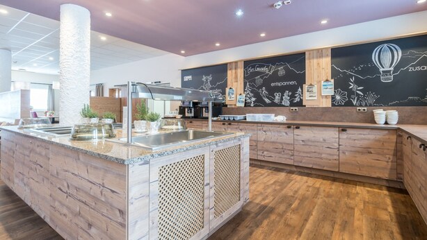 A modern kitchen with a granite countertop, stainless steel appliances, and a chalkboard wall with travel-themed artwork. - Pleasant Apartment in Gosau near Ski Area (Gosau)