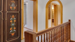 Una escalera de madera con barandilla que conduce a una habitación con una puerta de madera decorada con motivos florales.
