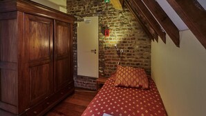 A small, cozy room with a wooden wardrobe, a single bed with a patterned bedspread, a brick wall, and a door with a sign. - Spacious Villa near Town Center in Mesch (Eijsden)