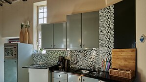 A compact kitchen with grey cabinets, a tiled backsplash, and a black countertop. - Spacious Villa near Town Center in Mesch (Eijsden)