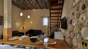 A dining area with a wooden table, white chairs, and a wall of decorative plates. - Spacious Villa near Town Center in Mesch (Eijsden)