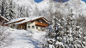 A chalet with a wooden balcony, surrounded by snow-covered trees and mountains. - Chalet in Filzmoos With Sauna & Mountain Views (Filzmoos)