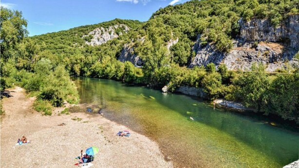 Ein klarer Fluss, umgeben von üppiger Vegetation und steilen Felswänden.