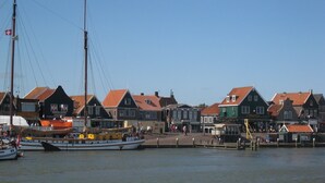 Ein Hafen mit traditionellen Häusern, einem vertäuten Boot und blauem Himmel.