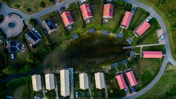 An aerial view of a residential area with houses, a small lake, and a winding road.