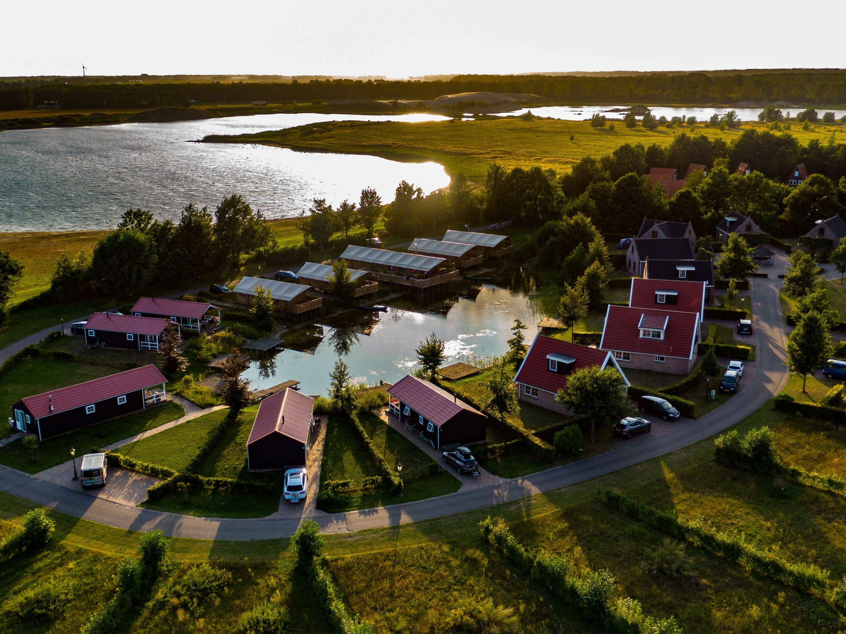 Vue aérienne d’une propriété au bord du lac, avec plusieurs maisons, un quai et une route.