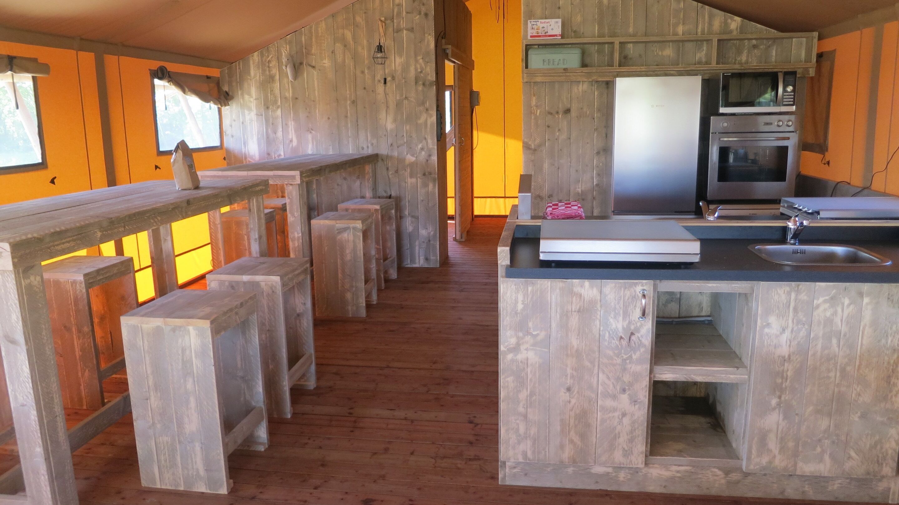 Une cuisine rustique avec des murs et des bancs en bois, un four encastré et un évier.