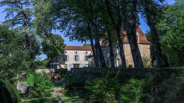 A stone building with a red-tiled roof, surrounded by lush greenery and trees. - Retreat Near Siorac-en-perigord (Saint-Germain-de-Belvès)