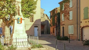 A narrow street with a statue, buildings with shutters, and a clear sky. - Contemporary Villa With Pool (Plan-de-la-Tour)