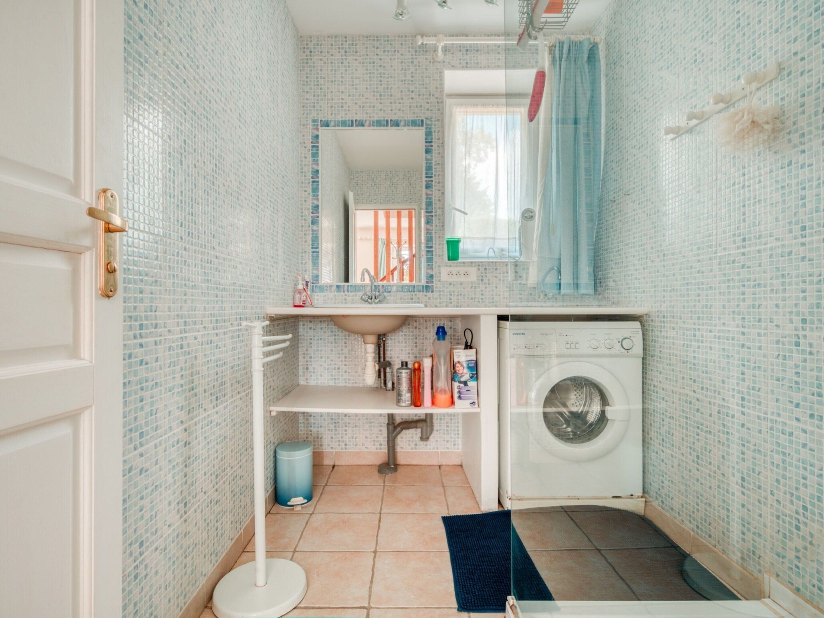 A compact bathroom with a sink, mirror, and washing machine.