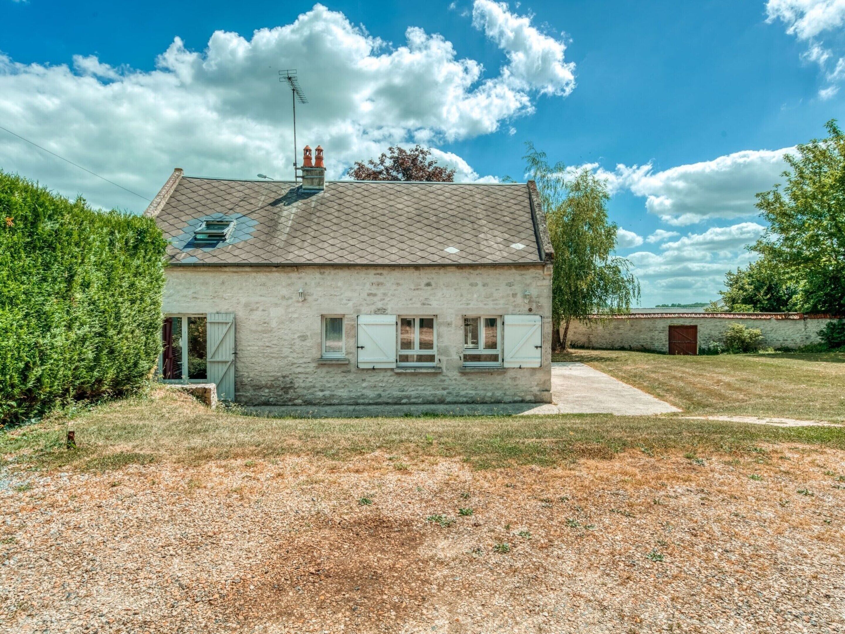 Une maison de plain-pied avec un toit en pente, une cheminée et un petit porche.