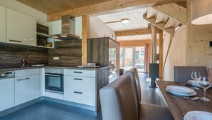Eine moderne Küche mit weißen Schränken, einem eingebauten Backofen und einer Holzbalkendecke.