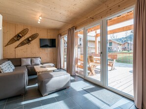 Et moderne interiør med en sofa, skærmpude og et fladskærms-tv monteret på en trævæg.