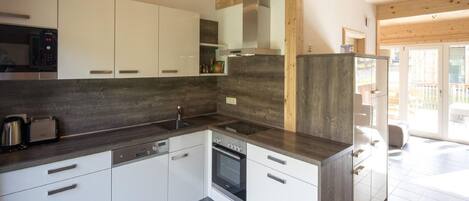 Una cocina moderna con armarios blancos, encimeras oscuras y un horno empotrado.
