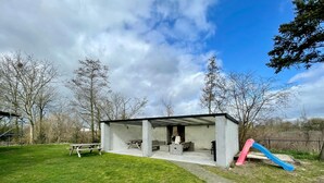 A concrete outdoor shelter with a fireplace, seating, and a picnic table. - Holiday Home in Elsendorp With Garden (Elsendorp)