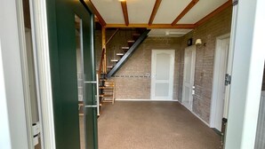 A hallway with a carpeted floor, a staircase with wooden railings, and a door at the end. - Holiday Home in Elsendorp With Garden (Elsendorp)