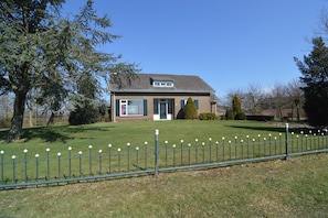 A house with a fenced yard, a lawn, and a large tree. - Holiday Home in Elsendorp With Garden (Elsendorp)