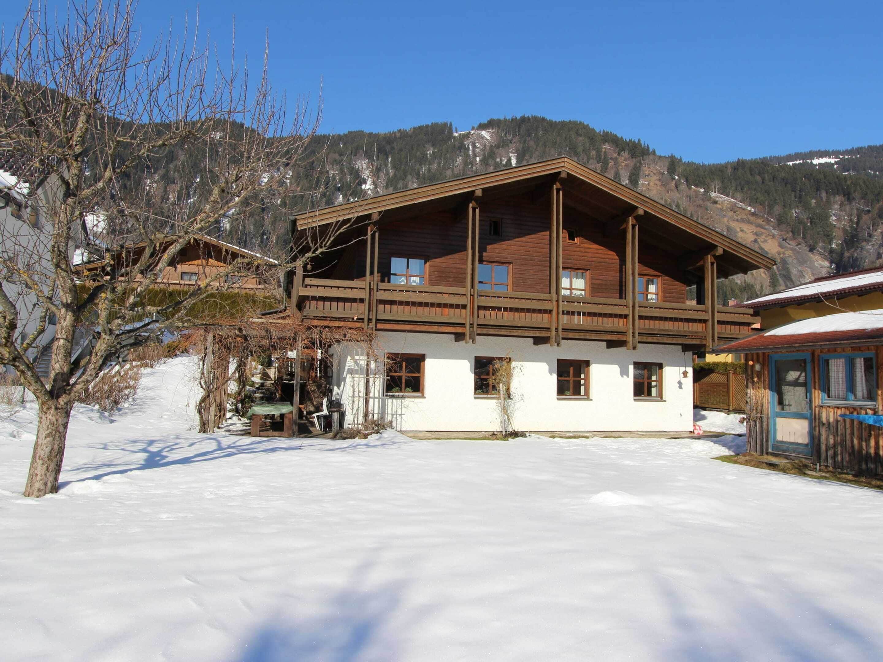 Una cabaña de madera con balcón, rodeada de nieve y montañas.