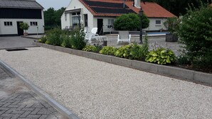 Un patio con piso de grava, sillones blancos para relajarse y una pequeña zona de piscina.