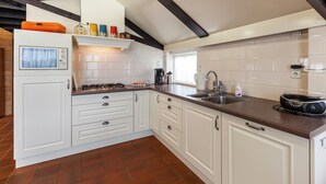 Una cocina con armarios blancos, una estufa y un lavabo.