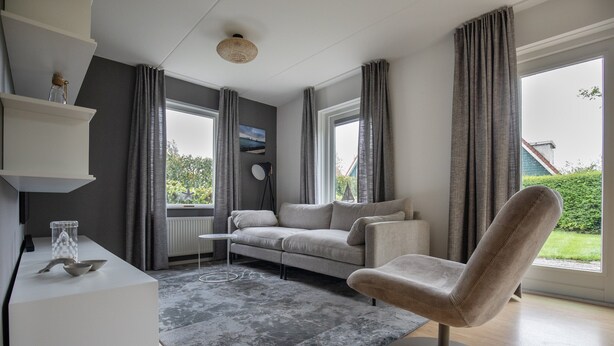 A modern living room with a grey sofa, a round chair, a white console table, and a grey rug. - Detached Holiday Home near Grevelingenmeer Lake (Zonnemaire)