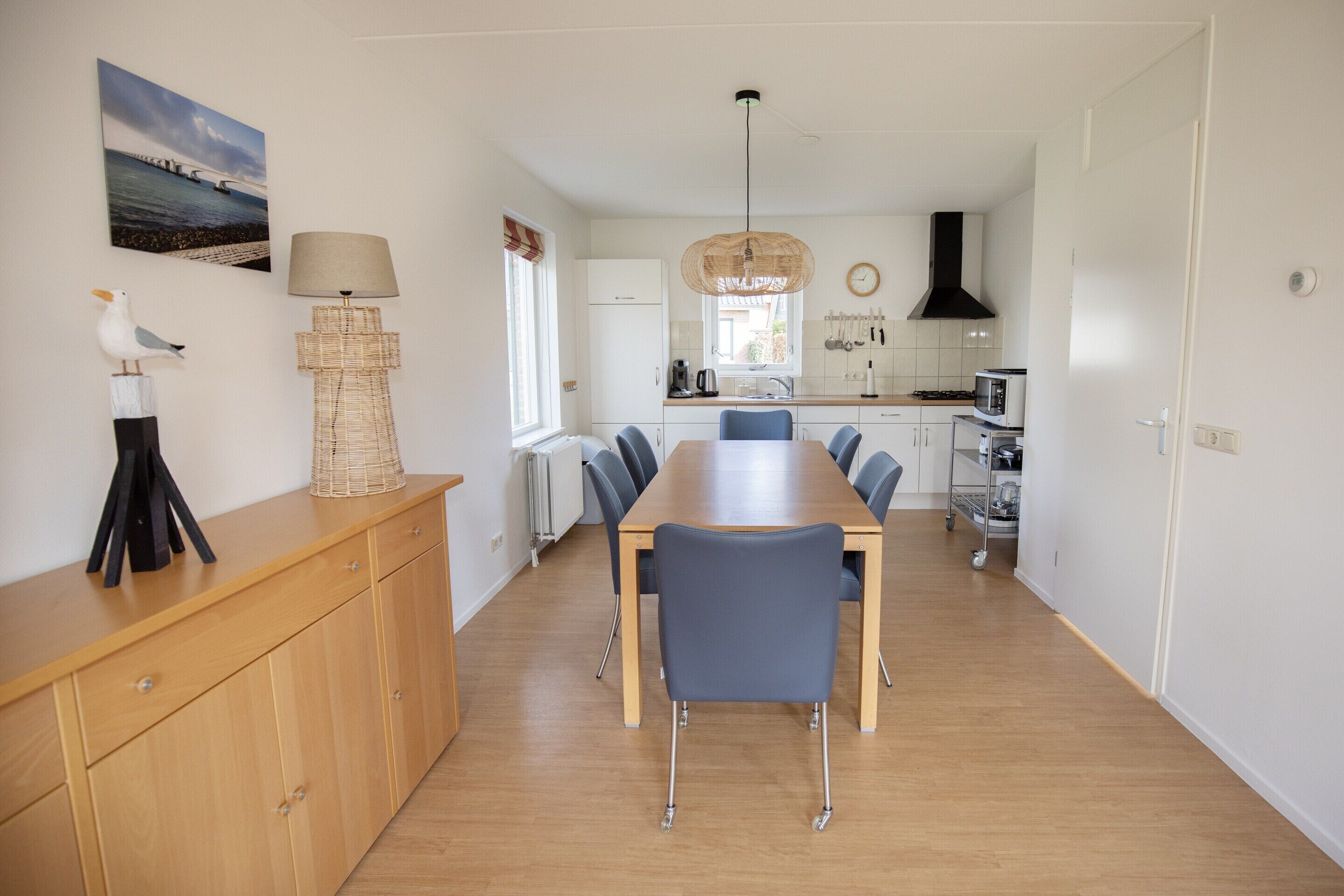 Una cocina moderna con comedor, que incluye una mesa de madera, sillas y una lámpara colgante.