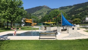 A park with a water play area, a slide, and a blue canopy structure. - Boutique Apartment With Mountain View (Brixen im Thale)