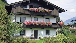 A two-story building with balconies adorned with flowers, a front door, and a small outdoor seating area. - Splendid Apartment in Fugen near Ski Area (Fuegen)