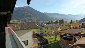 A residential area with a view of snow-capped mountains, a paved courtyard, and a wooden pergola with parked cars. - Splendid Apartment in Fugen near Ski Area (Fuegen)