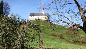 A church with a red steeple on a grassy hill. - Splendid Apartment in Fugen near Ski Area (Fuegen)