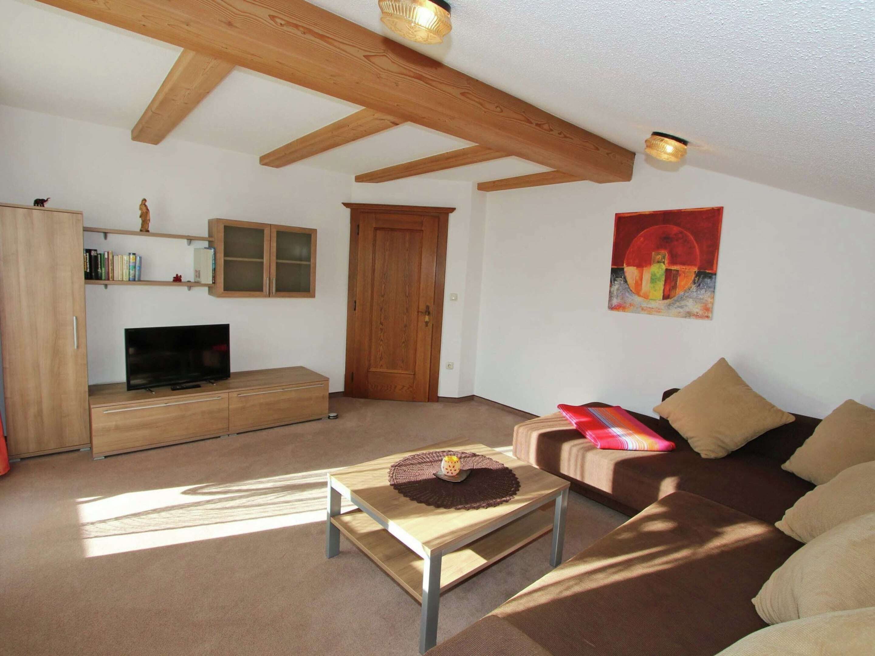 A living room with a TV, wooden furniture, a door, and a painting.