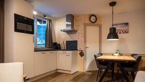 A compact kitchen with a window, built-in oven, and a dining area with a wooden table and chairs. - Welcoming Apartment in Sankt Margarethen im Lungau near Ski Area (Sankt Margarethen im Lungau)