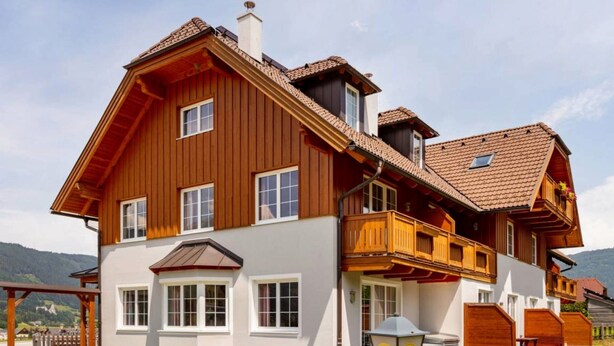 A large two-story wooden house with a balcony, a garage, and a well-maintained lawn. - Welcoming Apartment in Sankt Margarethen im Lungau near Ski Area (Sankt Margarethen im Lungau)