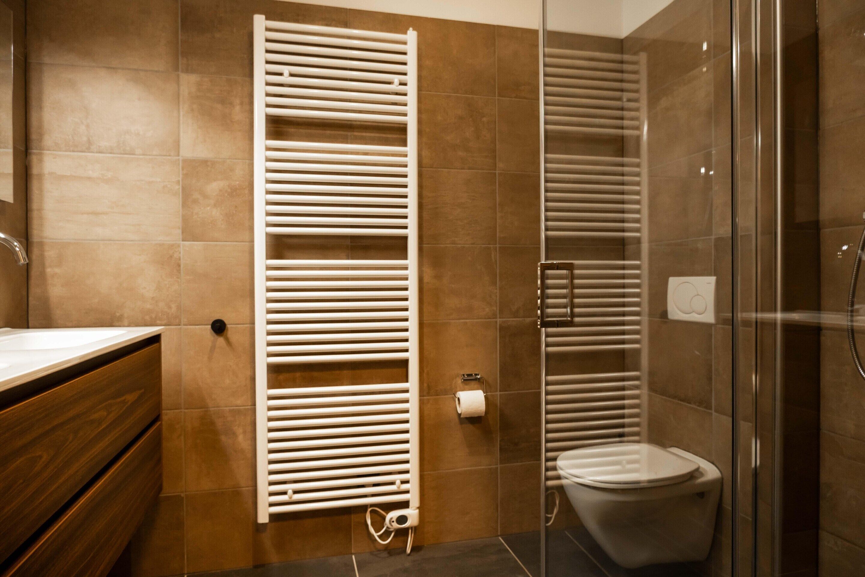 A modern bathroom with a glass shower enclosure, a toilet, and a towel rack.