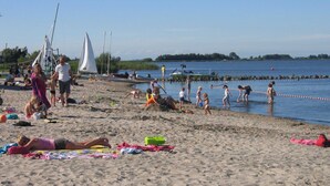 Ein Strand mit Menschen, die sich sonnen, schwimmen und spielen.