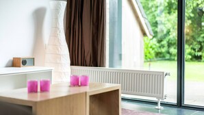 Ein modernes Zimmer mit Schreibtisch aus Holz, einem weißen Heizkörper und Blick auf Grünfläche.