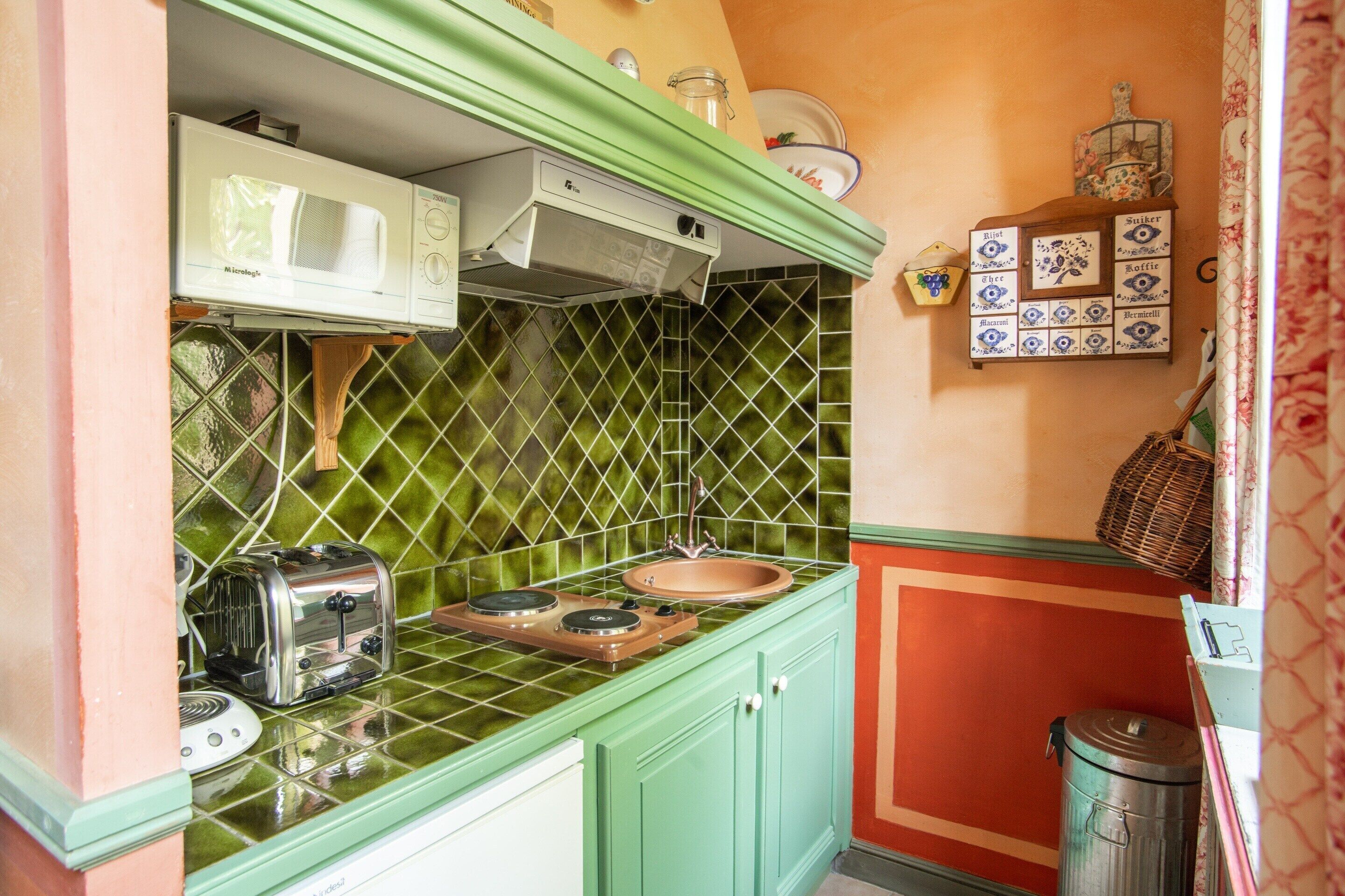 Une cuisine avec un plan de travail vert, un micro-ondes blanc, un grille-pain et un évier.