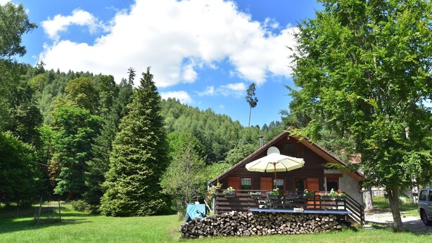 A wooden cabin with a patio, surrounded by trees and a clear sky. - Quiet Chalet With Garden (Saint-Quirin)