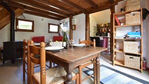 A dining area with a wooden table, chairs, and a bookshelf. - Quiet Chalet With Garden (Saint-Quirin)