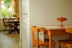 A dining area with a table, chairs, and a fruit bowl.