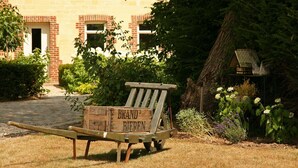Ein hölzerner Wagen mit der Aufschrift "BRAND BIEREN" in einem Garten, im Hintergrund ein Gebäude.