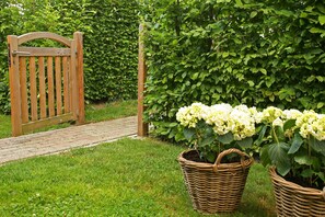 A wooden gate, a brick pathway, and two wicker baskets with plants. - Farmstay With Garden Views (Wijlre)