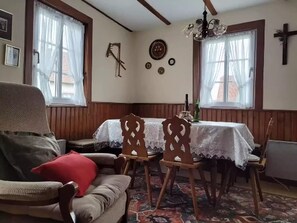 A room with a wooden ceiling, a dining table with chairs, a sofa, and a cross on the wall. - Holiday Home Alsace Near Vosges Nature Park (Schleithal)