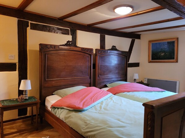 A bedroom with a wooden headboard, a bedside table with a lamp, and a painting on the wall. - Holiday Home Alsace Near Vosges Nature Park (Schleithal)