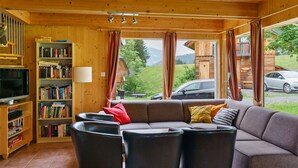 Una sala de estar acogedora con un sofá modular, una estantería y un televisor.