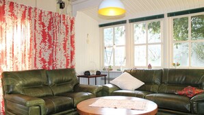 A living room with a green leather sofa, a round wooden coffee table, and a patterned rug.
