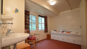A bedroom with a bed, a window, a sink, and a chair.