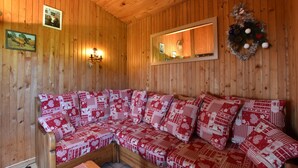 A wooden-paneled room with a sofa, wall-mounted light fixtures, and a mirror. - Chalet in Saulxures Near Ski Resorts (Saulxures-sur-Moselotte)