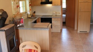 Una cocina compacta con una isla central, estufa, fregadero y armarios de madera.
